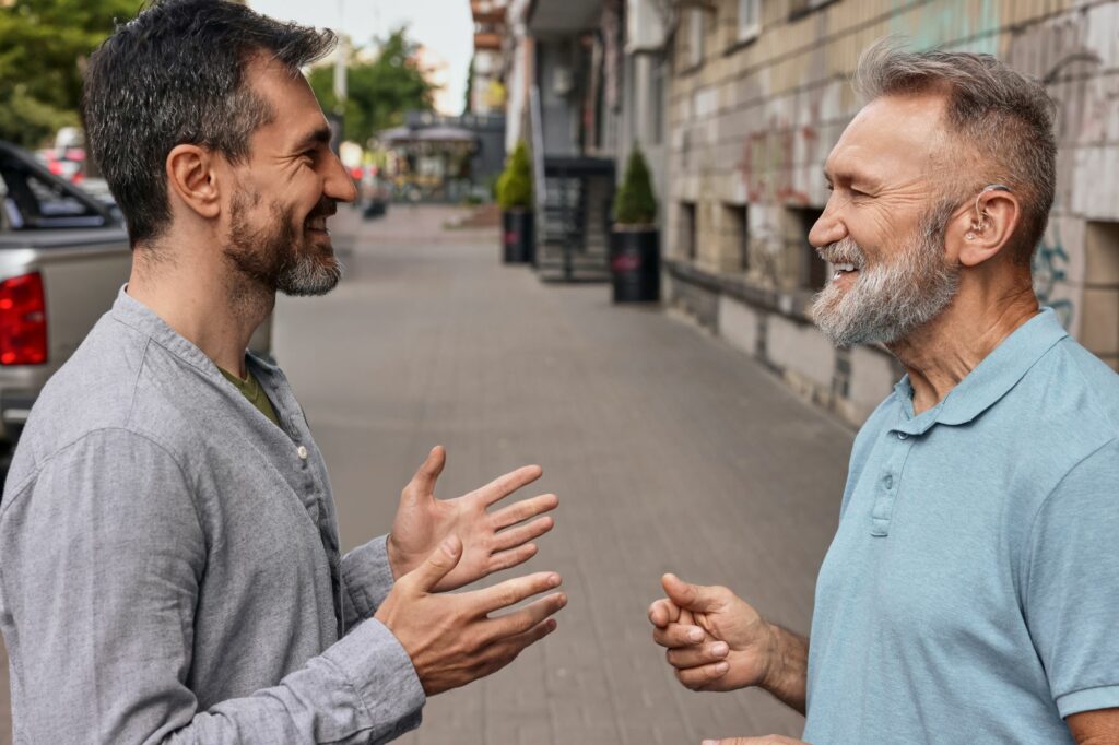 two-smiling-men-chatting-on-city-street-2026-03-25-06-08-08-utc